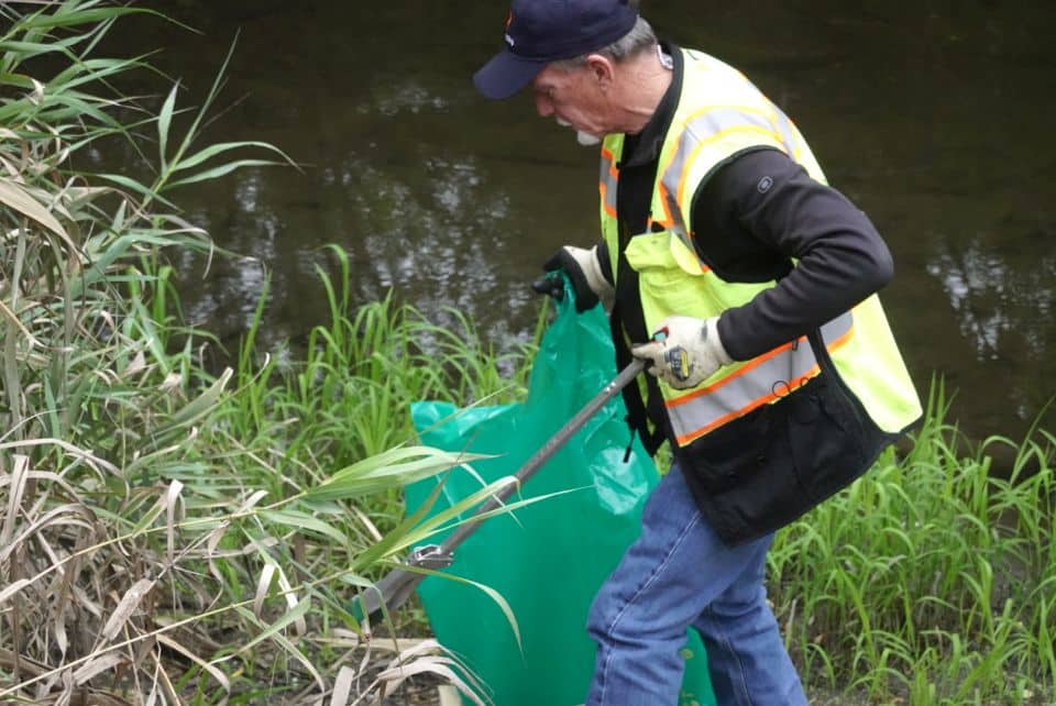volunteer picking up trash along creek